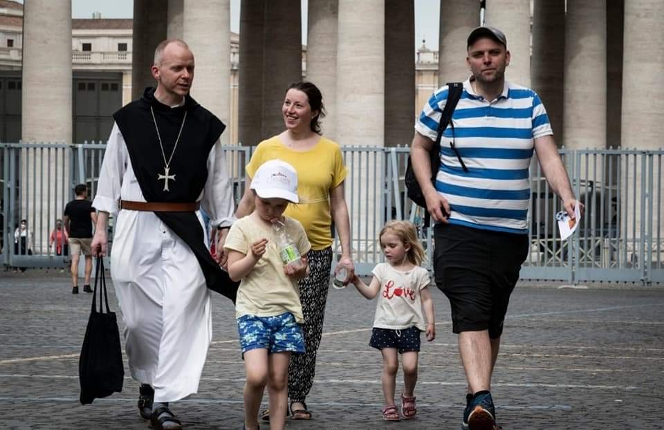 En gruppe voksne og barn går sammen over Petersplassen i Roma.